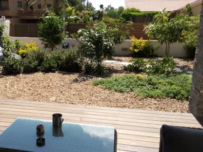 גינה בחזית הבית עם רסק עץ במקום מדשאה